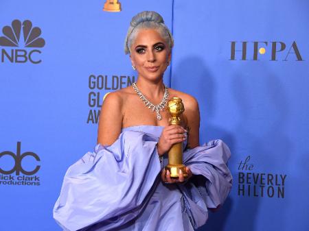 Lady Gaga posa para os fotógrafos no Globo de Ouro com seu prêmio de melhor canção - Mark Ralston/AFP