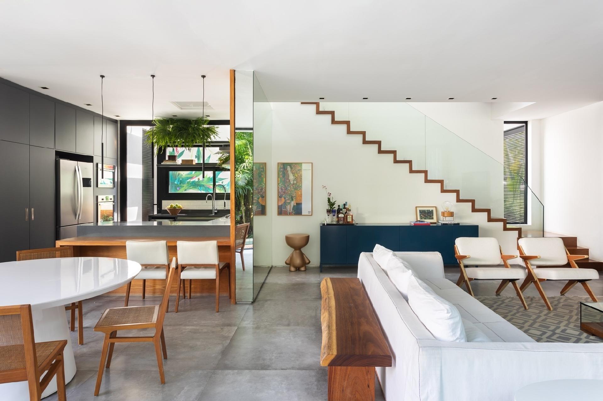 Dessa base branca saltam as cores neutras - o azul marinho entre elas - no grande living integrado. Cimento, madeira, branco e serralheria preta compõem uma base neutra no piso térreo, enquanto as tonalidades aparecem pontualmente. - Luiza Schreier/Divulgação