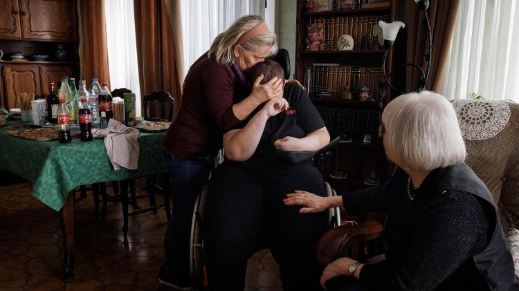 Lydie Imhoff é abraçada pela amiga e cuidadora Marie Josee Rousseaux e pela ativista do direito à morte Claudette Pierret durante sua festa de despedida em Longwy, norte da França, em 31 de janeiro de 2024.