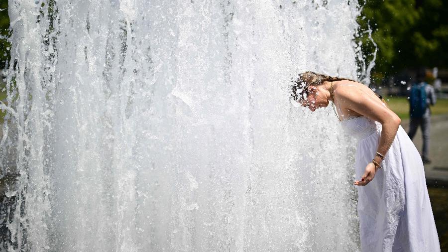 Uma jovem mergulha a cabeça na água fresca de uma fonte no parque Lustgarten, em Berlim Uma jovem mergulha a cabeça na água fresca de uma fonte no parque Lustgarten, em Berlim