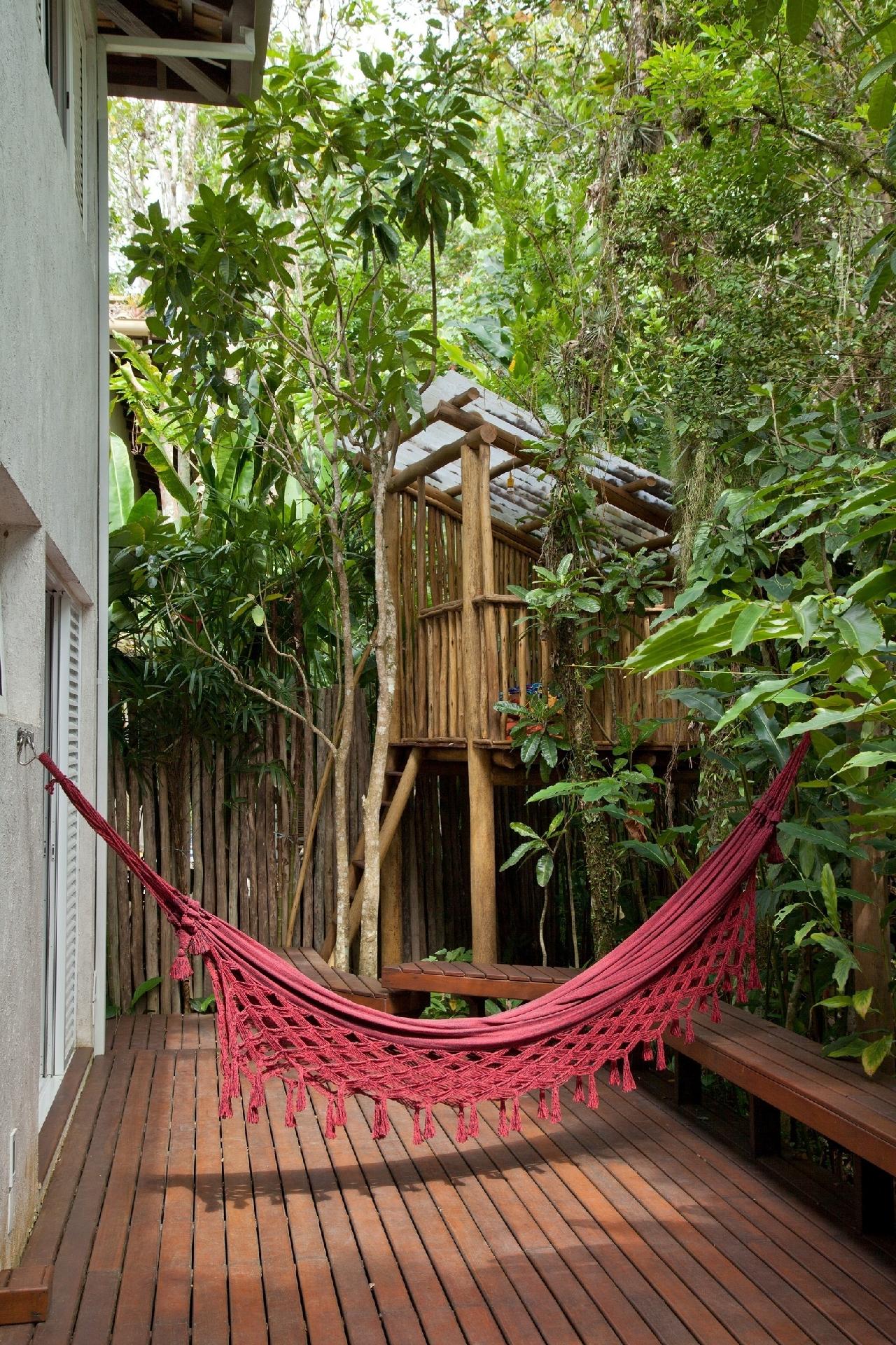Nesta casa de praia, a arquiteta Luciana Uras, do Studio ArquitetUras, dispôs a rede nos fundo do terreno, aproveitando o entorno repleto de árvores onde também foi instalada uma casinha na árvore para as crianças. Os ganchos devem ficar a cerca de 1,70 m de altura e o centro da rede convém estar a aproximadamente 60 cm do chão. A distância entre os ganchos dependerá do tamanho da rede - Luis Gomes/Divulgação
