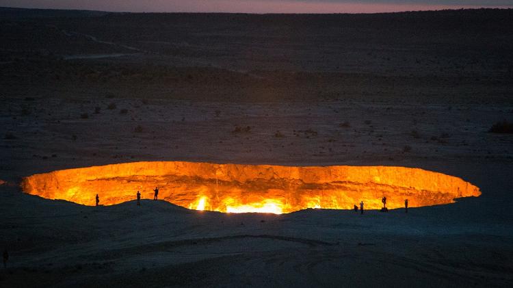 Pessoas ficam minúsculas na frente da "Porta para o Inferno", no Turcomenistão  - Getty Images/iStockphoto - Getty Images/iStockphoto