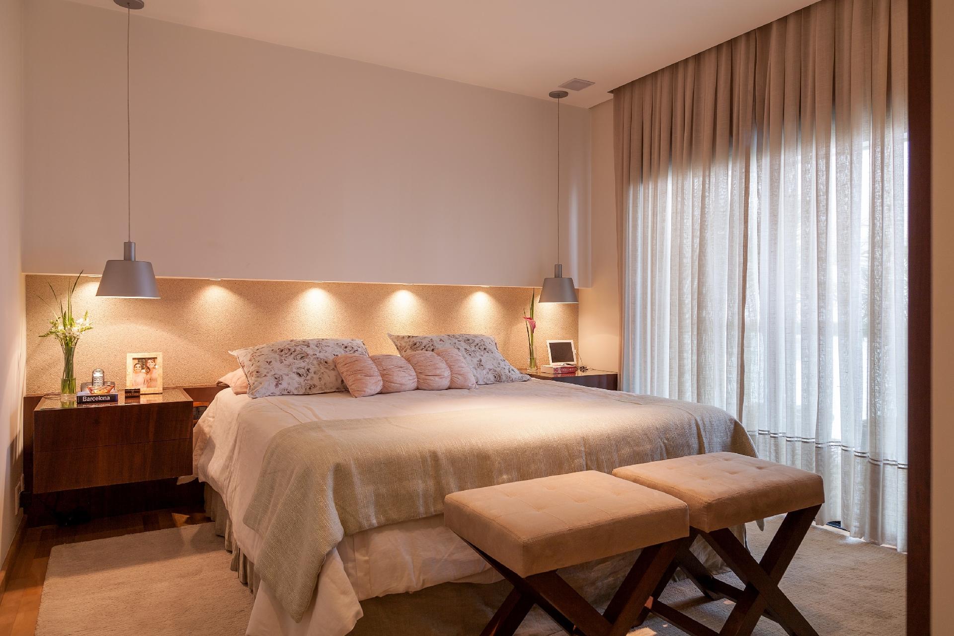 Um módulo de marcenaria em madeira imbuia vai de uma ponta a outra e traz em si dois criados-mudos acoplados e suspensos. Esta área mais baixa valoriza o papel de parede logo acima. O revestimento é composto por mica, que ganha ainda mais brilho com a iluminação embutida no drywall, projetado como se fosse a continuidade do forro de gesso. Projeto da arquiteta Cláudia Xavier - Júlia Ribeiro/ Divulgação