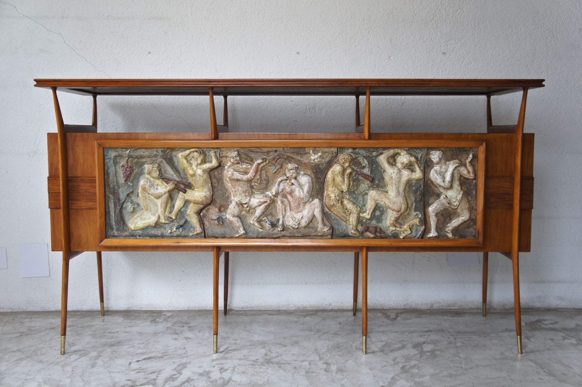 Bar (1955), desenhado pelo arquiteto Giuseppe Scapinelli, com aplicações em cerâmica vitrificada que retratam personagens dionisíacos. O móvel é constituído por uma caixa de madeira (caviúna) apoiada sobre finos pés-palito e sua forma lembra os pilotis de Le Corbusier - Divulgação