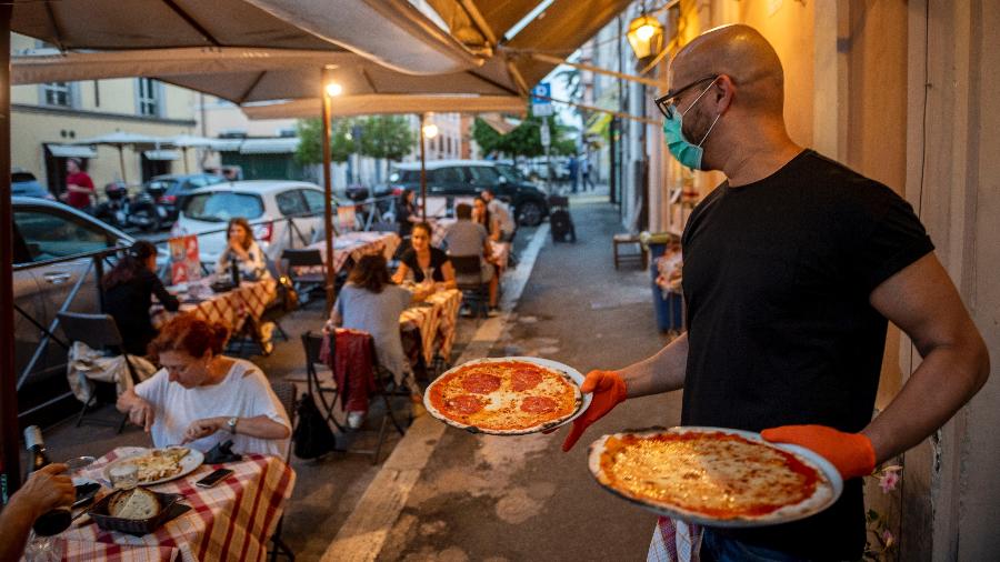 Garçom serve pizzas em restaurante próximo ao Coliseu, em Roma - Getty Images