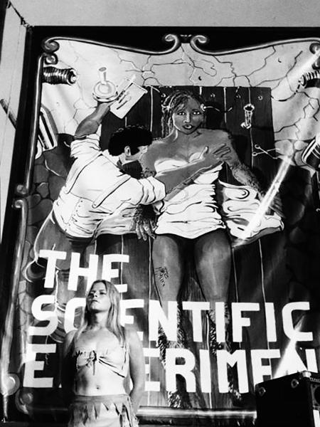 Uma jovem artista americana se posiciona em frente ao cartaz que anuncia seu show de mulher-gorila, em meados dos anos 80. O número adquiriu características próprias no Brasil e nos EUA - Diane Falk - Diane Falk