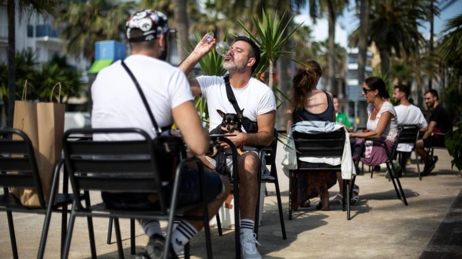 Pessoas sentam-se em mesas externas de restaurantes em Barcelona - Getty Images