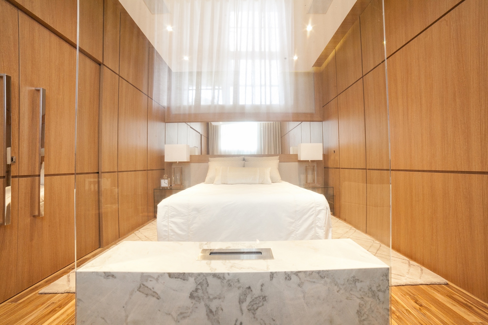 6 - Suíte do casal jovem. O quarto desenvolvido por Luciana Hara segue a linha contemporânea, definida pelo uso da madeira e das cores neutras. No espaço, a arquiteta inova ao projetar a TV em um painel de vidro incolor e transparente, junto à lareira (em primeiro plano). A Casa Cor Paraná fica em cartaz até dia 9 de agosto de 2015, na Rua Fernando Amaro, 60, em Curitiba. Outras informações: www.casacor.com.br - Daniel Sorrentino/ Divulgação