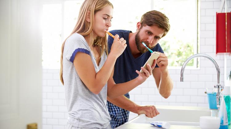 Casal escovando os dentes/ Escovar os dentes com celular - iStock - iStock
