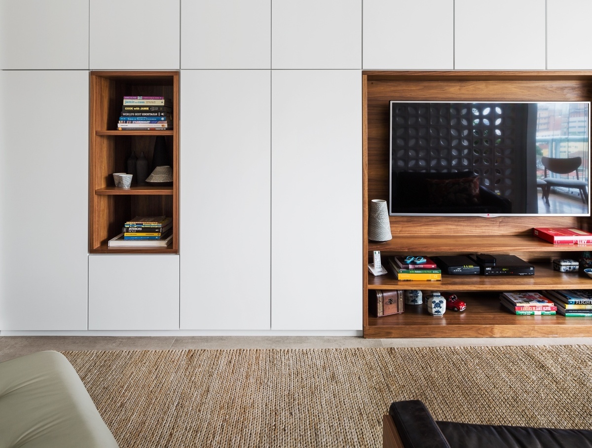 Todo branco e com nichos em nogueira, o armário medindo 4,5 m de extensão acomoda tudo: roupas, livros, material de limpeza, aparelhos de home theater, cafeteira e até adega. O projeto de reforma é da arquiteta Marcela Madureira - Ana Mello/ UOL