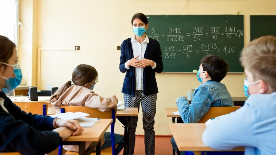 Professora em sala de aula com máscara de proteção facial em meio à pandemia do coronavírus - iStock