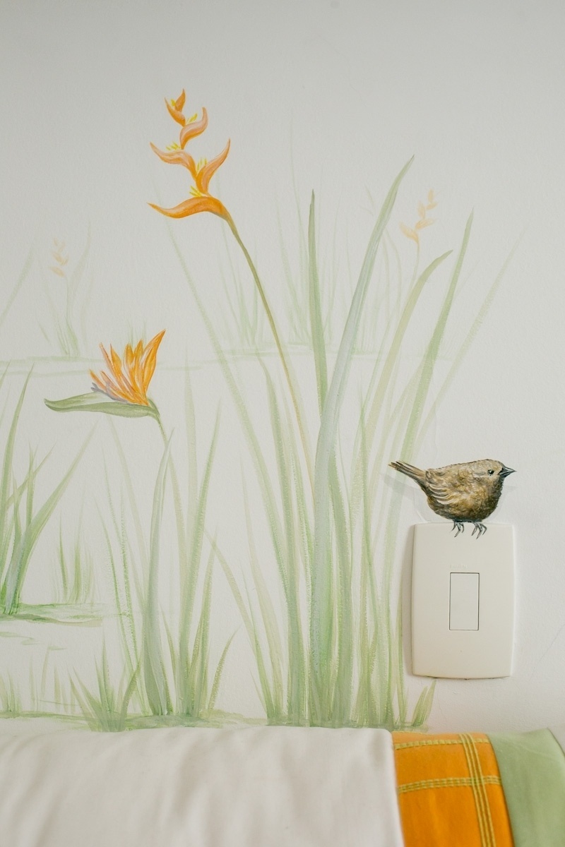 A pintura na parede deste quarto de bebê --projetado pelo escritório Ambienta Arquitetura-- foi feita pelas artistas plásticas Gogó e Pimpa Alcantara (www.gogoepimpa.com.br). A partir do gosto da mãe pela flor strelitzia, as artistas criaram todo o cenário ao redor, que incluiu pássaros como este da foto, desenhado com traços delicados acima do interruptor de luz - Lela Beltrão/Divulgação