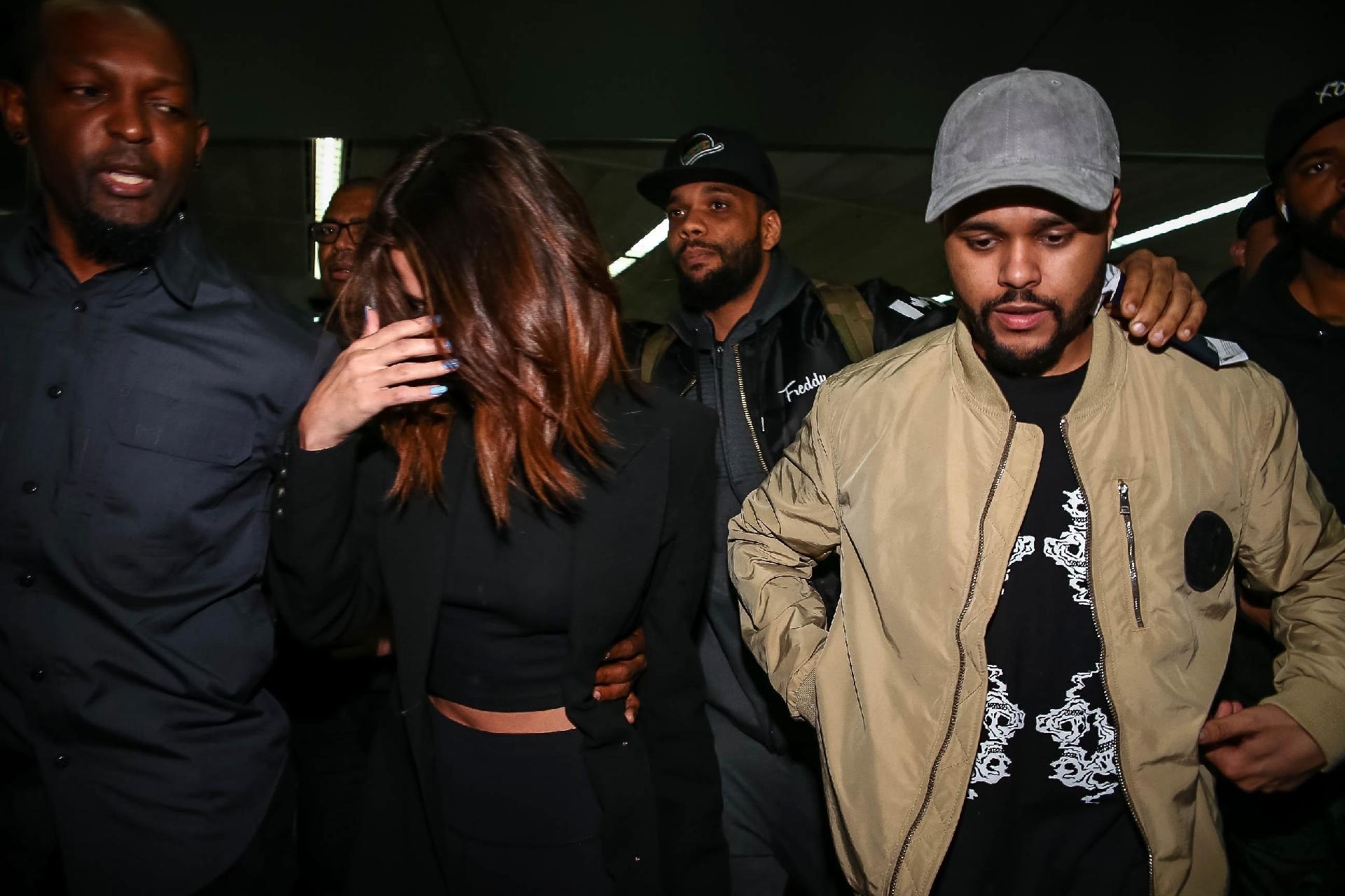 Em meio a tumulto, Selena Gomez e The Weeknd desembarcam no aeroporto de Guarulhos, em São Paulo sob forte escolta de seguranças - Raphael Castello/AgNews
