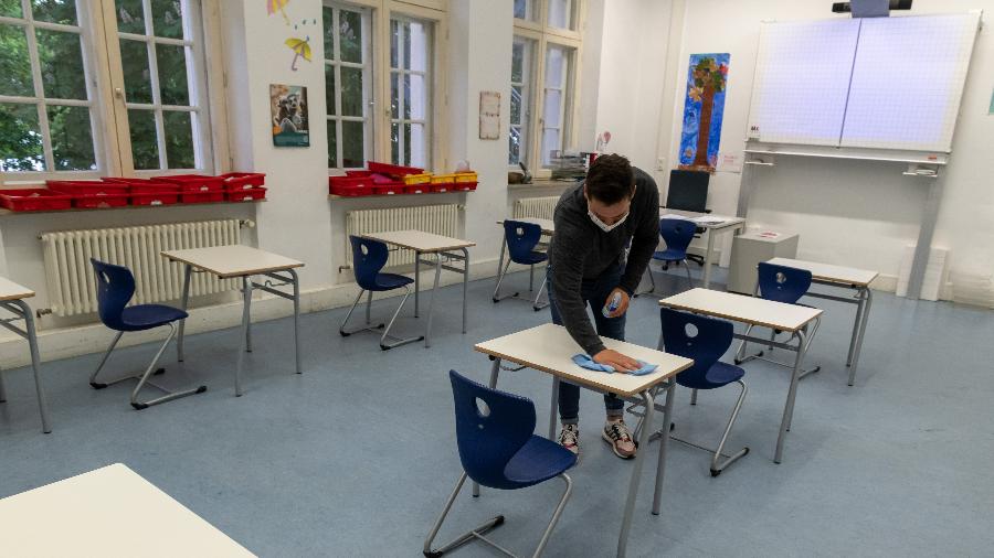 Professor desinfeta mesas em sala de aula para receber alunos  em Munique, na Alemanha - Getty Images