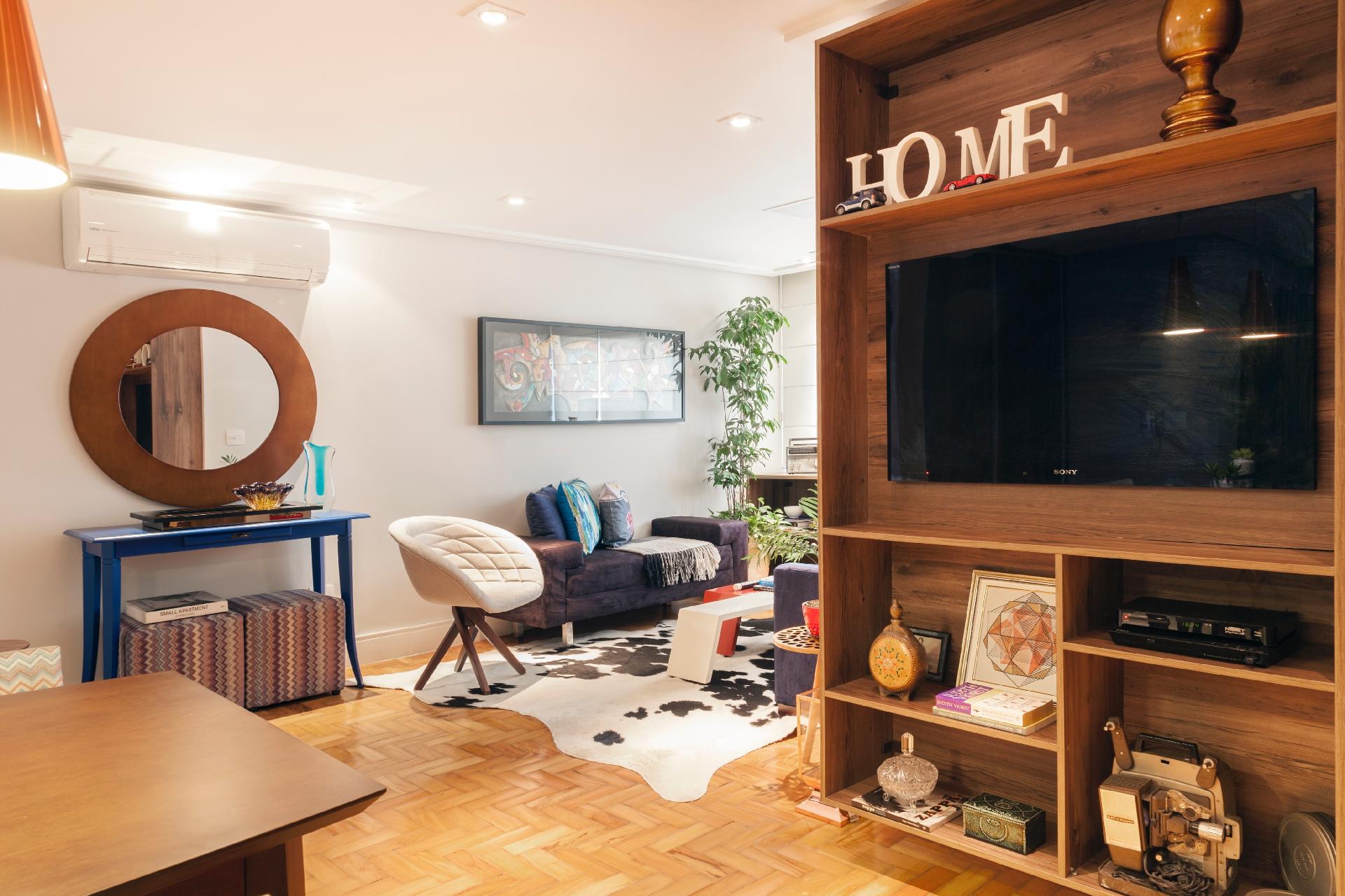 A parede que delimita a área íntima do apê e forma a quina no estar, na reforma idealizada pelo escritório Biarari & Rodrigues, foi ocupada por um móvel planejado que abriga o 'home theater' e que pode ser usado da sala de jantar e da cozinha. Em diversos tamanhos, os nichos comportam equipamentos e objetos de decoração - J. Vilhora/ Divulgação