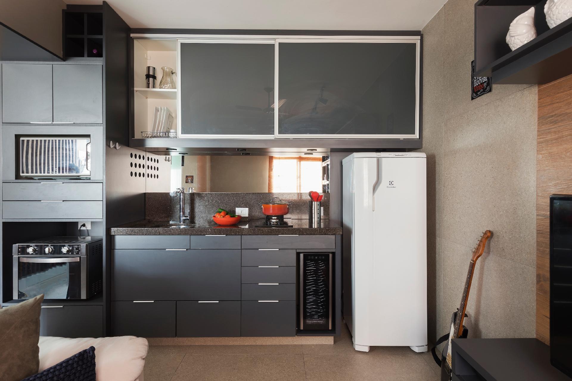 Com armários sob medida, a cozinha é funcional. O módulo vertical acomoda forno e micro-ondas, além de seguir até o teto e dispor de lugar para as garrafas de vinho - Rafael Renzo/Divulgação