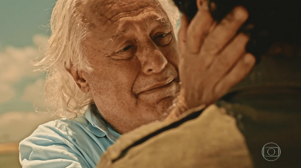 Durante passeio pela praia com Iolanda, Afrânio vê a imagem do filho Martim e lhe dá um abraço caloroso - Reprodução/TV Globo