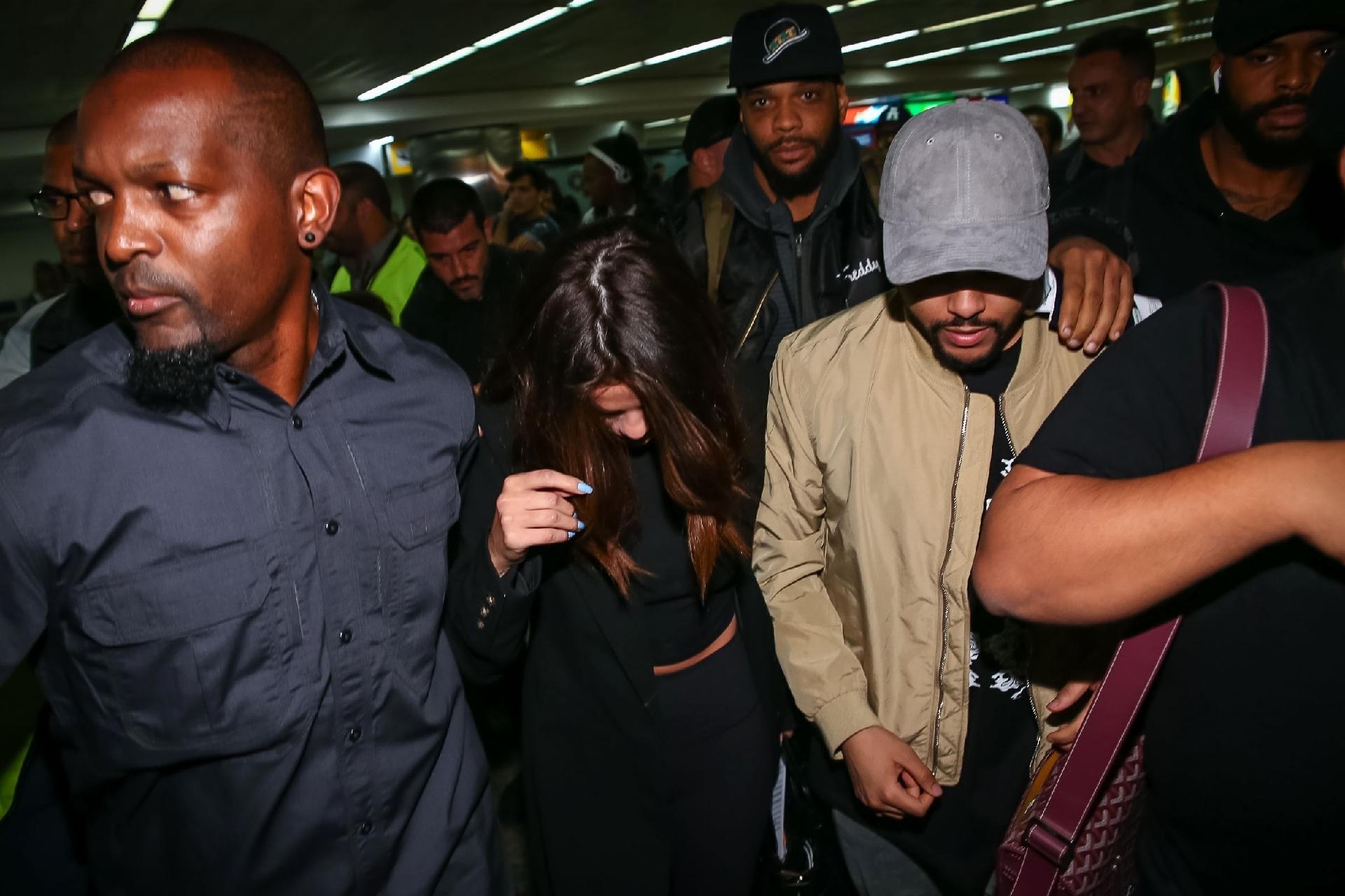 Em meio a tumulto, Selena Gomez e The Weeknd desembarcam no aeroporto de Guarulhos, em São Paulo sob forte escolta de seguranças - Raphael Castello/AgNews