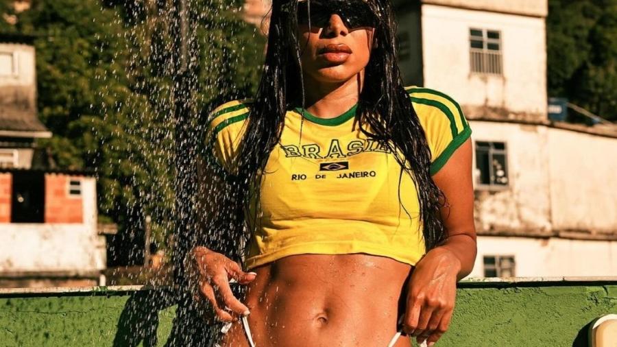 Anitta posa em laje com short ultracavado e camisa do Brasil para clipe