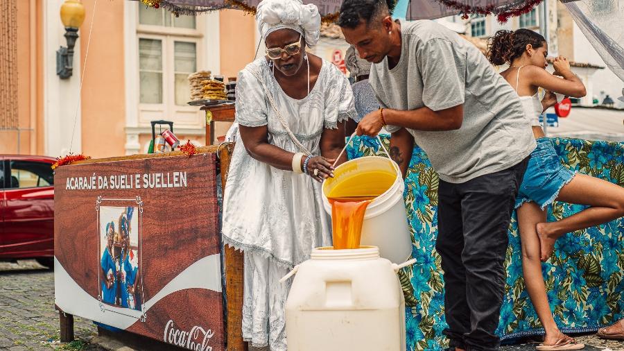 Colaborador da startup ÓiaFia! recolhe azeite de dendê que sobrou da produção de acarajé, em Salvador