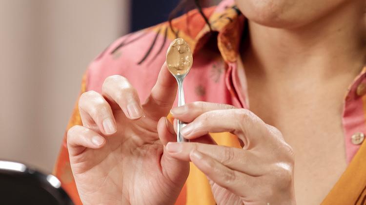 Fabi mostra a quantidade de base que deve ser aplicada, usando uma colher de café como medida - Mariana Pekin - Mariana Pekin