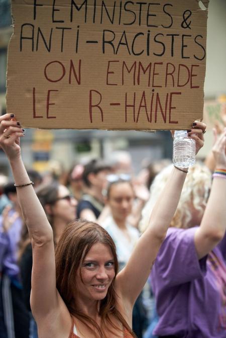 Mulher segura um cartaz que diz "Feministas e antirracistas: Nós incomodamos o ódio"
