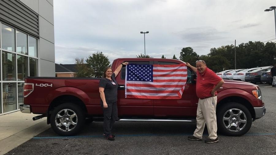 Cliente de concessionária da Ford posa com bandeira dos EUA após comprar carro - Divulgação