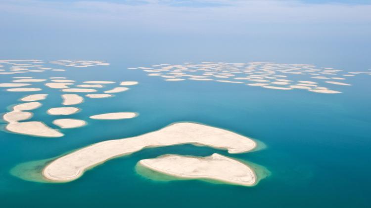 Vista aérea de Dubai nos Emirados Árabes Unidos, com ilhas ao centro.