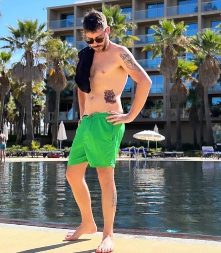 Evaristo Costa posa sem camisa à beira da piscina com tatuagem à mostra