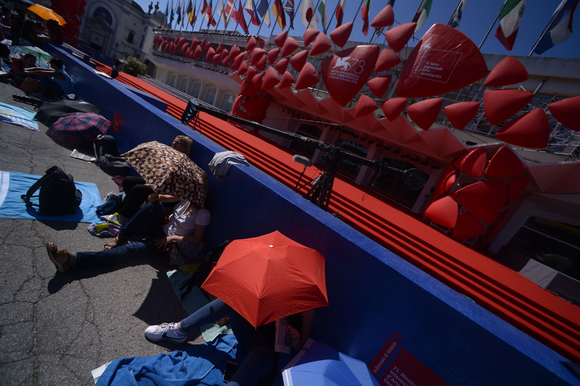 31.ago.2016 - Pessoas se protegem do sol enquanto aguardam em fila pela abertura do 73º Festival de Veneza, na Itália - Filippo Monteforte/AFP