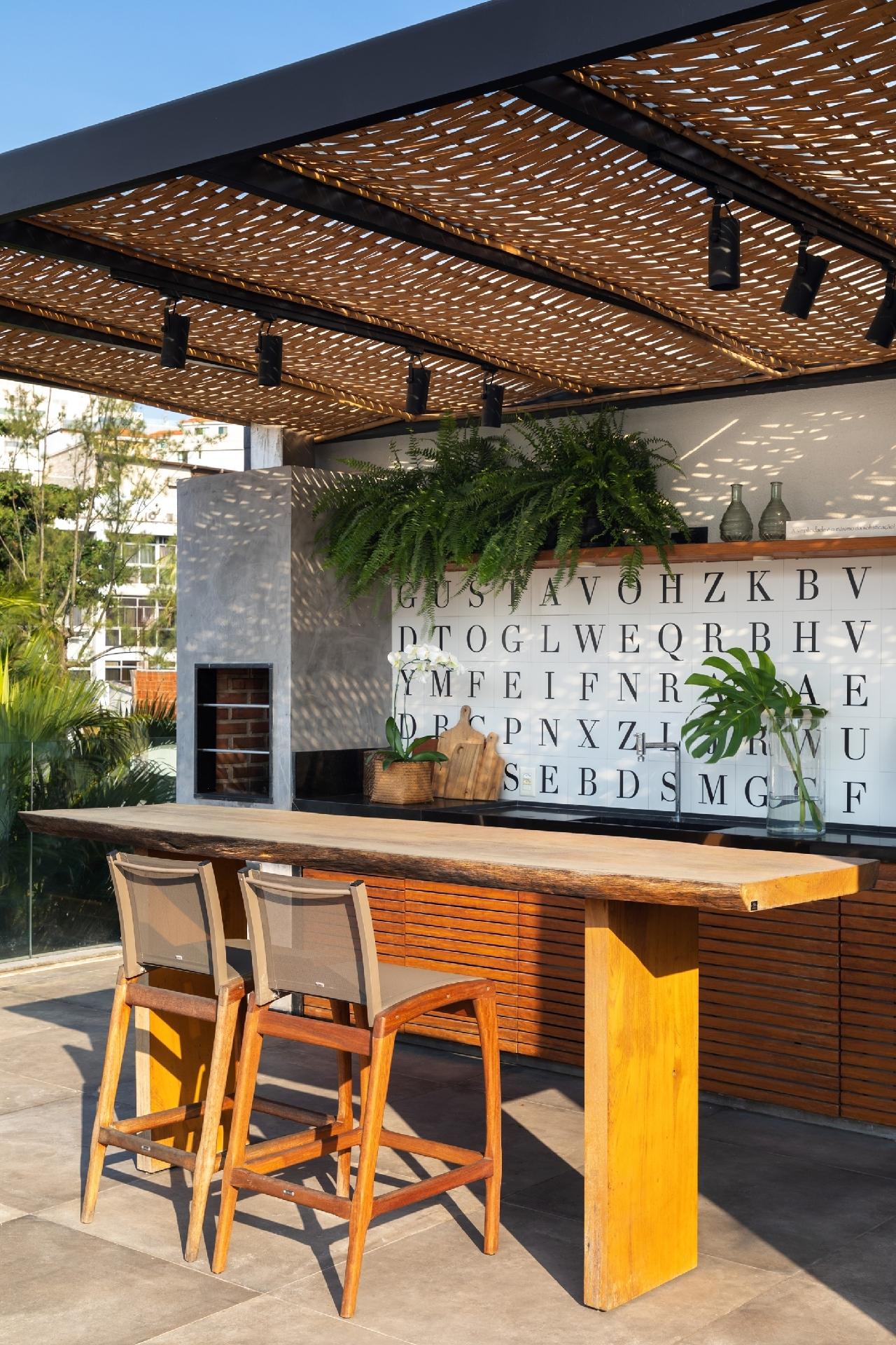 Sob o pergolado de estrutura metálica com trançado de bambu, que protege a área gourmet do sol e da chuva, o destaque é a parede com azulejos em um alfabeto, que sai do comum. - Luiza Schreier/Divulgação
