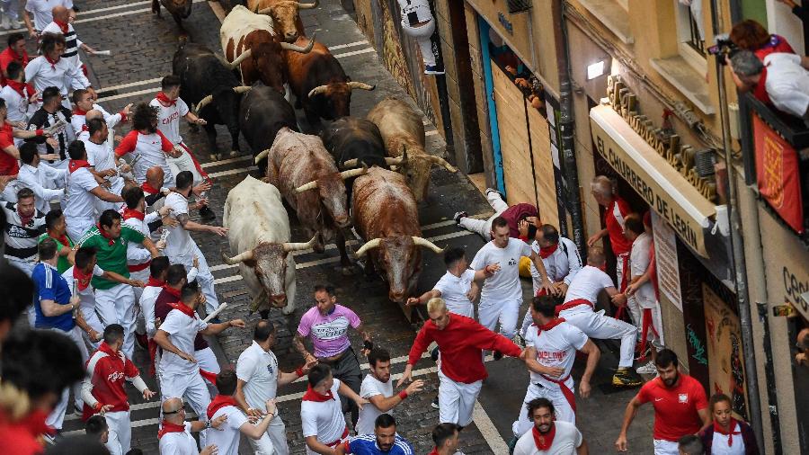 Participantes correm dos touros em Pamplona, no retorno da Festa de São Firmino após dois anos de pandemia - ANDER GILLENEA/AFP
