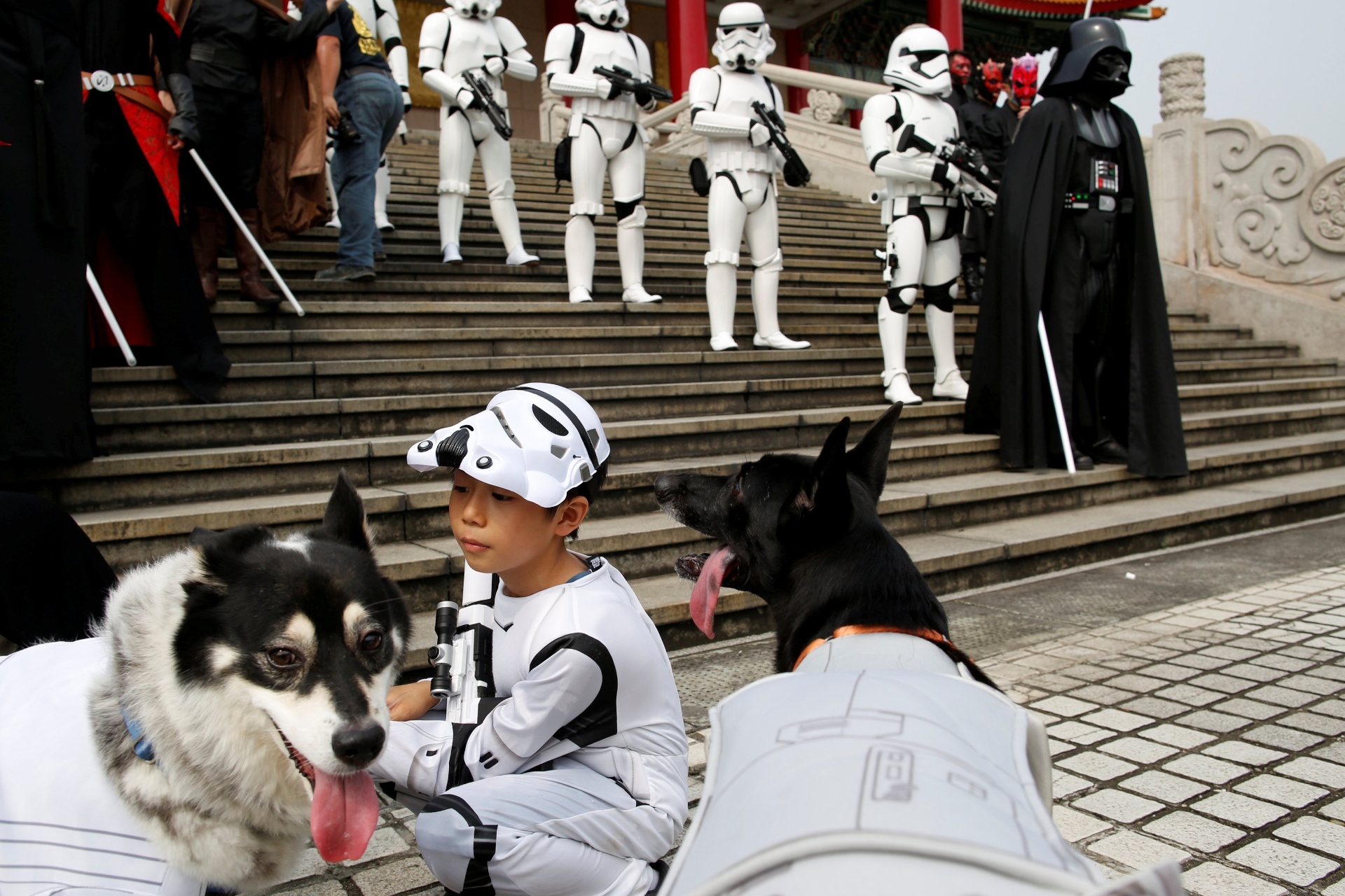 04.mai.2016 - Criança vestida como Stormtrooper de "Star Wars" brinca com um cachorro em Taipei, no Taiwan - Tyrone Siu/Reuters