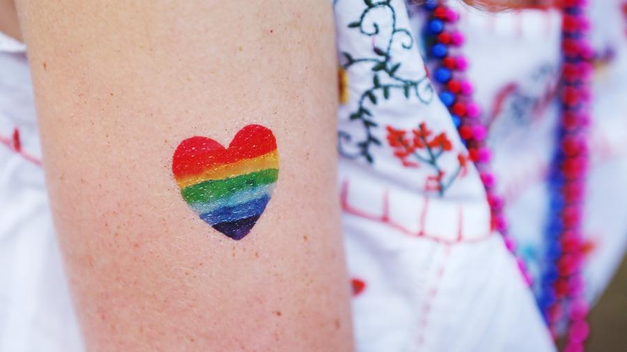 mulher com um coração de arco íris no braço, LGBT, LGBTQIA+
