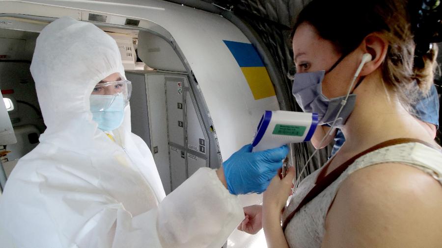 Passageiros passam por medição de temperatura ao entrarem em avião na Ucrânia - Getty Images