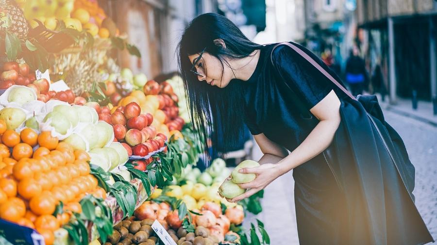 Mulher escolhendo frutas em feira orgânica