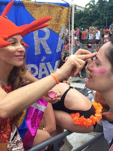 Maíra Inaê aplica purpurina biodegradável na professora Moema Duberley em bloco de Carnaval do Rio - Giovani Lettiere/UOL