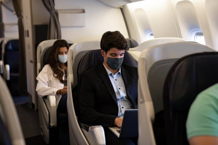 Business man traveling and wearing a facemask on the plane while using his laptopÃ¢ÂÂ COVID-19 pandemic lifestyle concepts - andresr/Getty Images - andresr/Getty Images