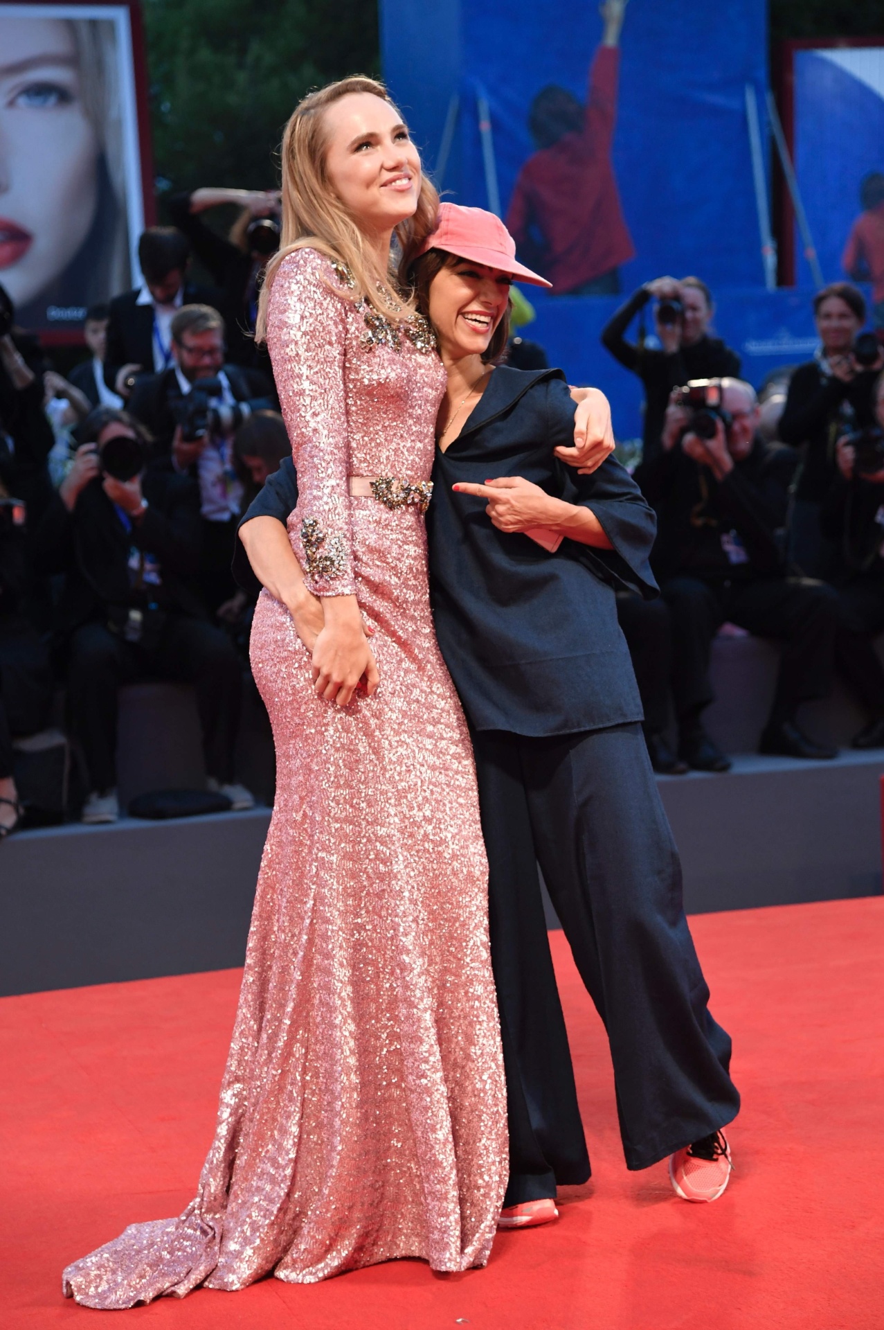 6.set.2016 - A diretora Ana Lily Amirpour escolheu uma roupa no estilo pijama, tênis e boné para a première de seu filme "The Bad Batch" no Festival de Veneza. Ana abraça a atriz Suki Waterhouse, estrela de seu filme, que concorre ao Leão de Ouro - Tiziana Fabi/AFP