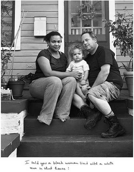 A fotógrafa Donna Pinckley optou por fazer os cliques em preto e branco e pediu para o casal escrever qual foi o pior insulto que ouviram. "Eu disse que uma mulher negra vivia com um homem branco nessa casa", ouviu o casal da imagem - Reprodução/Donna Pinckley
