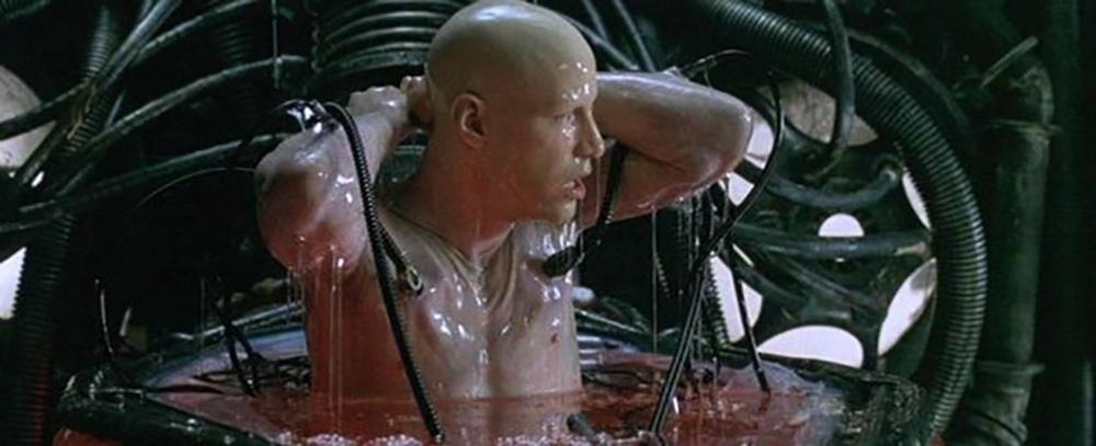 Nesta cena de "Matrix", vemos o personagem de Keanu Reeves acordando e retirando os eletrodos que o mantinham presos dentro da máquina - Divulgação