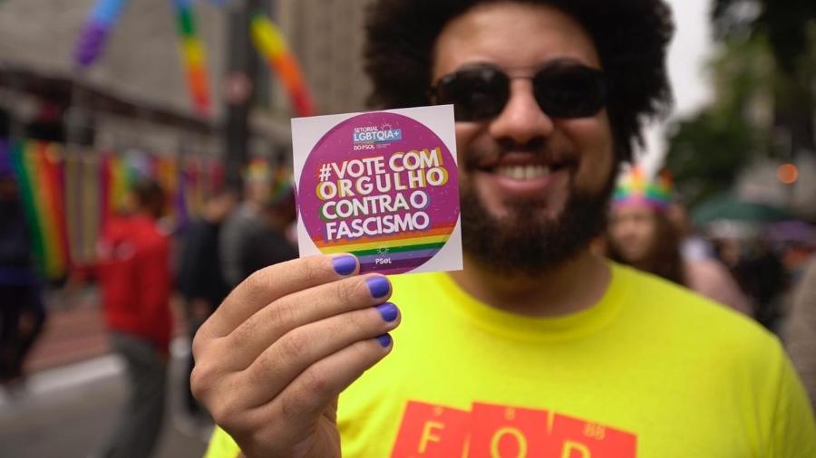 Participante da Parada LGBT+ mostra adesivo com tema do evento em 2022, "Vote com Orgulho" - André Porto/UOL