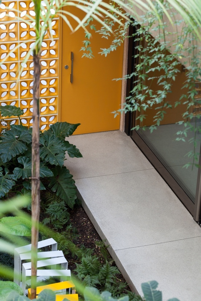 A passagem da garagem para a área social é marcada pela parede em cobogó amarela e pelos jardins. Banco Row, da A Lot Of. Placas de granilite claro revestem todo o piso da residência. A Casa Jardins foi projetada pelo escritório CR2 Arquitetura - Fran Parente/ Divulgação