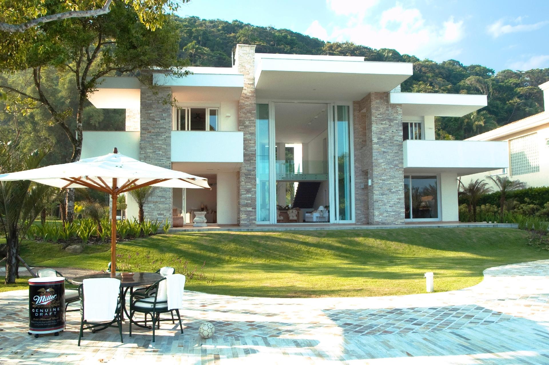 Toda área externa da casa no Guarujá (SP) é revestida de mármore travertino bruto. As portas de correr gigantes, em vidro e aço, também atraem olhares. A residência projetada por Itamar Berezin fica em uma área de 3.200 m². Quem assina a decoração é o escritório Barbara&Purchio - Rodrigo Erib/ Divulgação