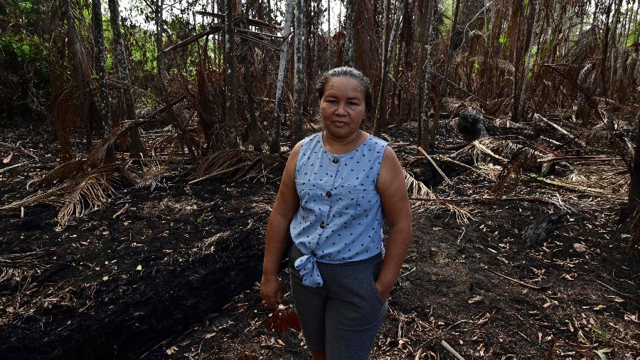 Giovana Serrão posa para uma foto em frente às suas palmeiras de açaí queimadas no Pará