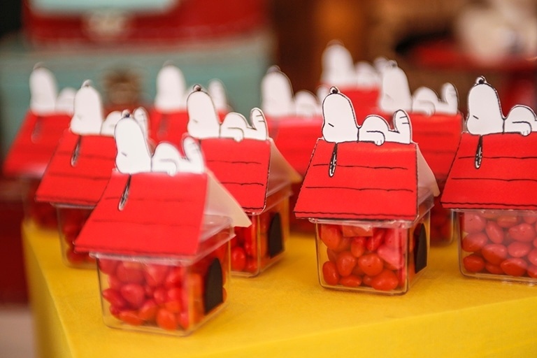 Balinhas de açúcar foram colocadas dentro de casinhas de acrílico com o cachorro Snoopy dormindo em cima. A decoração da mesa do aniversário foi assinada pela Caraminholando - Divulgação