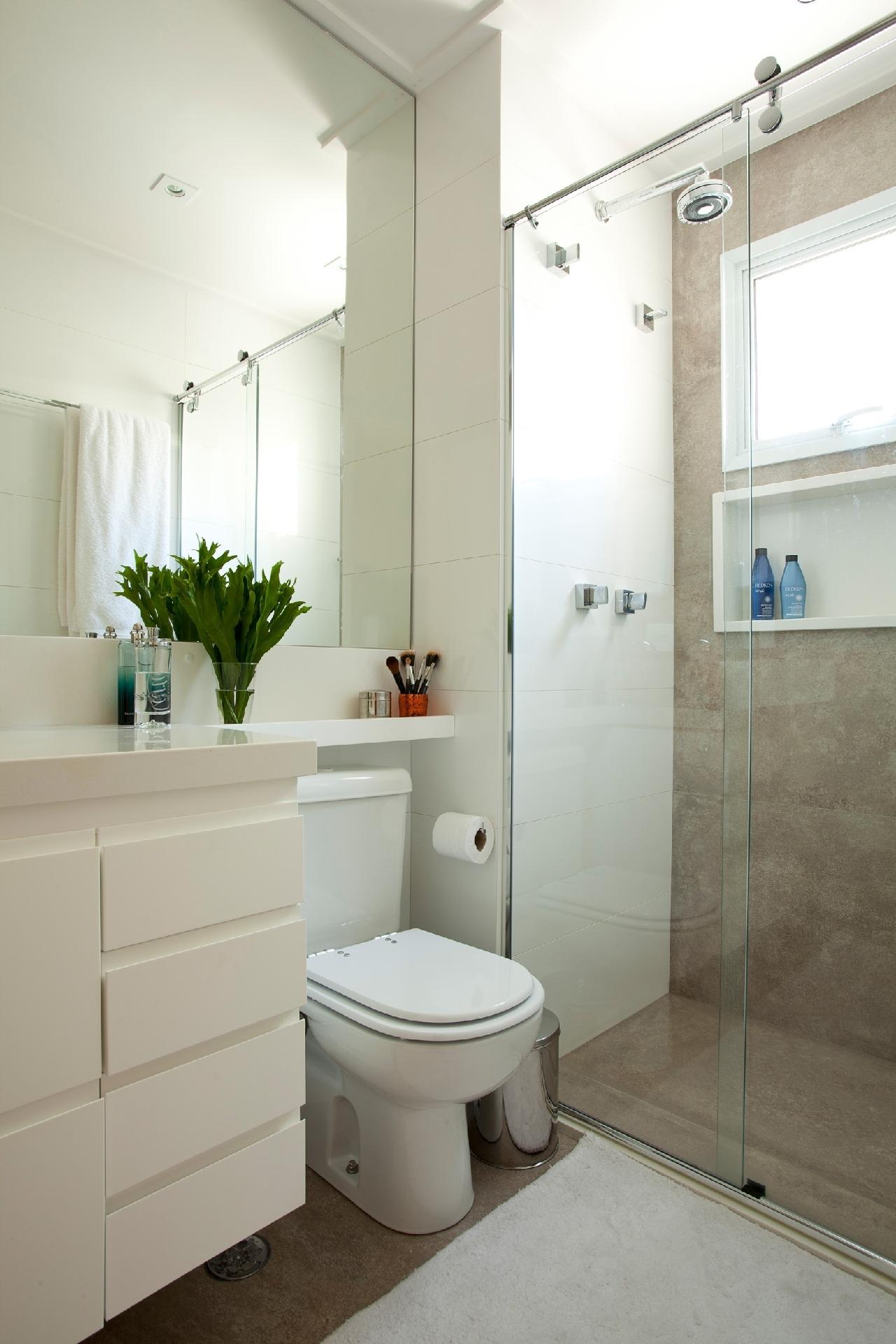 Portas de correr no boxe sempre economizam centímetros, assim como criar prateleiras no espaço acima do vaso sanitário. Além disso, a arquiteta Beatriz Quinelato usou um porcelanato de piso, que parece cimento queimado, em placas maiores, reduzindo a área de rejunte e fazendo o ambiente parecer maior - Adriana Barbosa | Divulgação