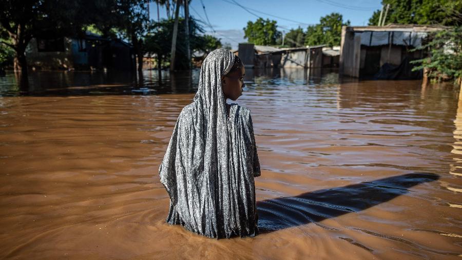 Mulher atravessa as águas de uma enchente no Quênia em 9 de maio de 2024