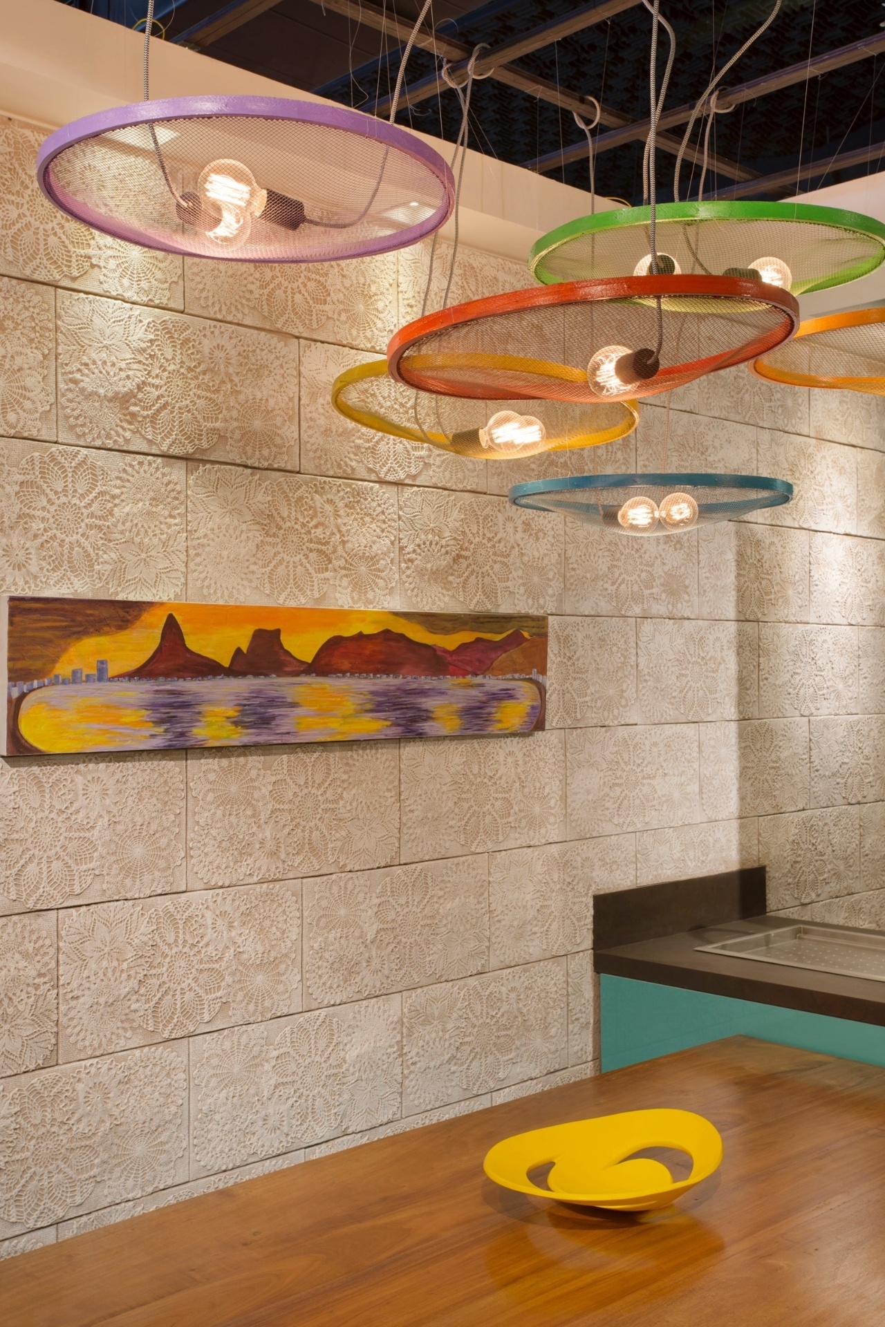 Quer uma luminária escultural e baratinha para sua sala de jantar? Copie a ideia de Ana Cano Milman, Lavínia Jobim e Érica Saraiva para o Estar Carioca da Morar Mais por Menos RJ. Pinte com diferentes cores os aros de seis peneiras, pendure-as em diversas alturas e apoie em cada uma das telas uma ou duas lâmpadas com bonitos filamentos de carbono | A mostra (www.morarmais.com.br) fica em cartaz até 2 de novembro de 2015 - MCA Estúdio/ Divulgação