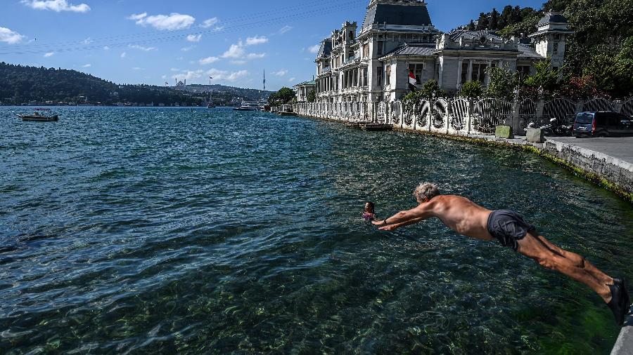Um nadador mergulha nas águas do estreito de Bósforo, no distrito de Bebek, em Istambul, em 29 de julho. A cena é comum na cidade e muitos residentes voltam para casa com o sal das águas entre dois continentes no corpo através do metrô - OZAN KOSE/AFP